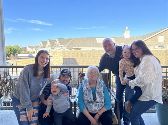 Family members celebrate joyfully together outside under a sunny sky.