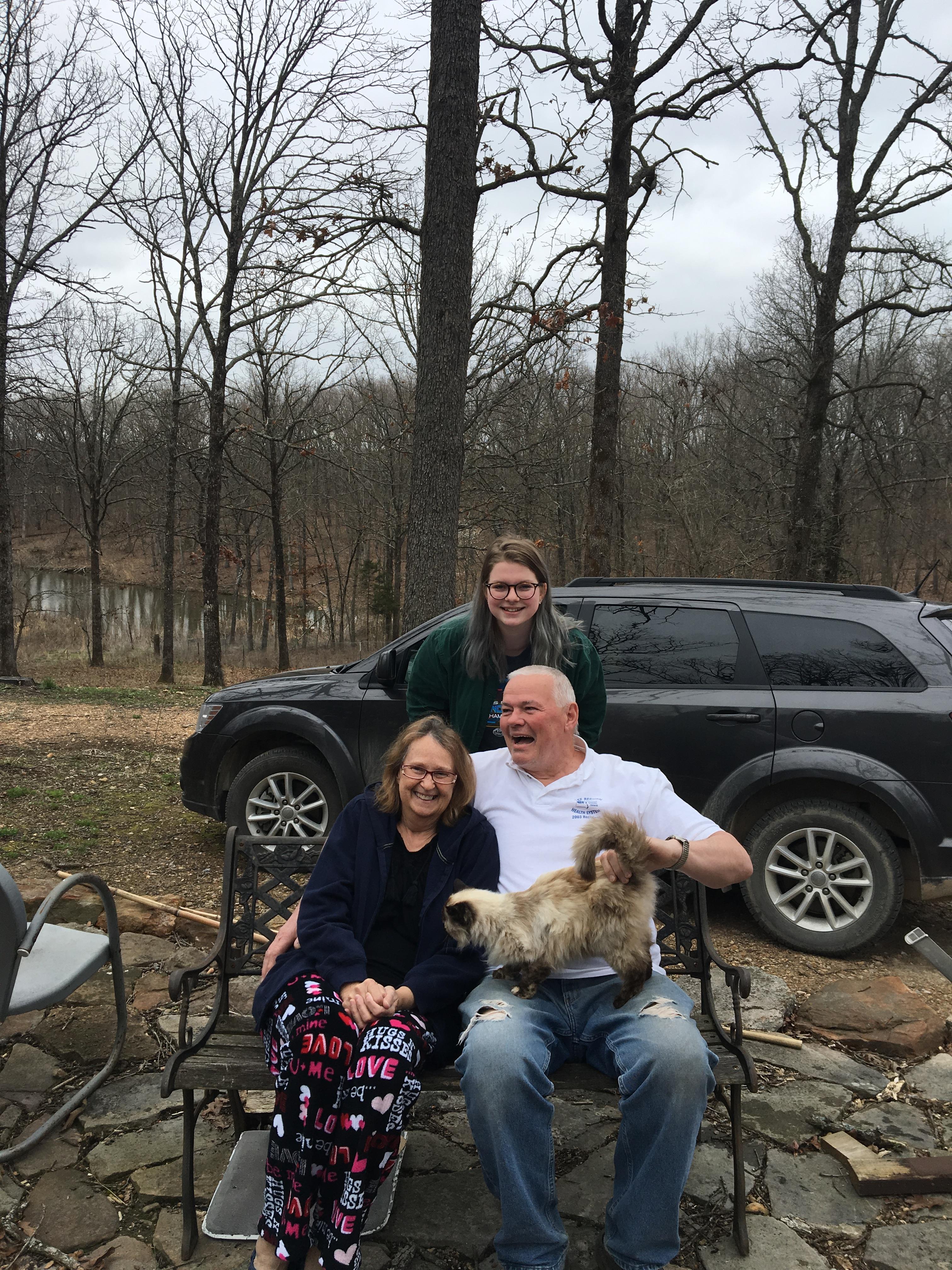 A group of people sitting on a chair with a dog