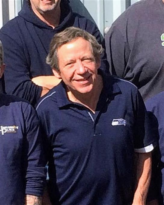 A joyful group of people stands together smiling against a bright backdrop, showcasing unity.