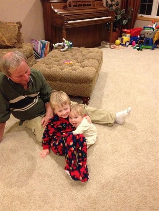 Grandfather enjoys quality time while playing with his two young grandchildren in a warm home.