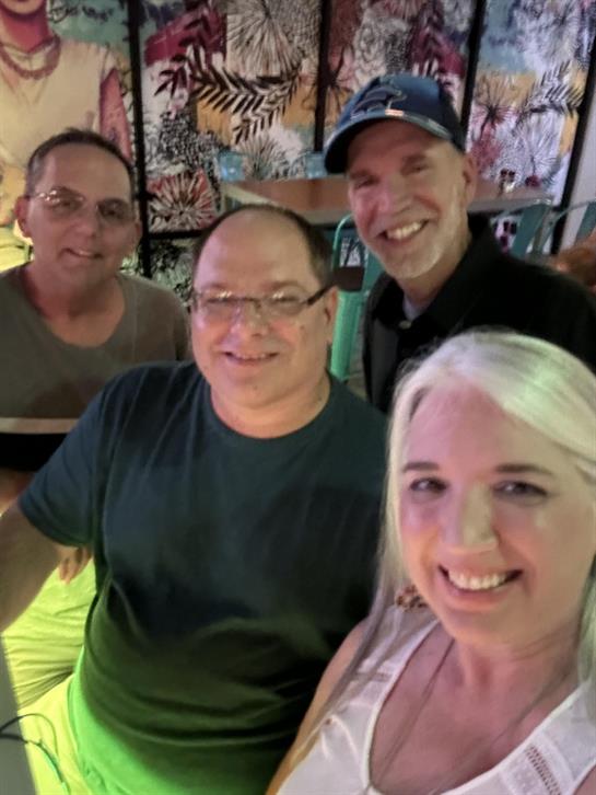 Four friends share smiles and laughter at a vibrant bar, enjoying their time together.