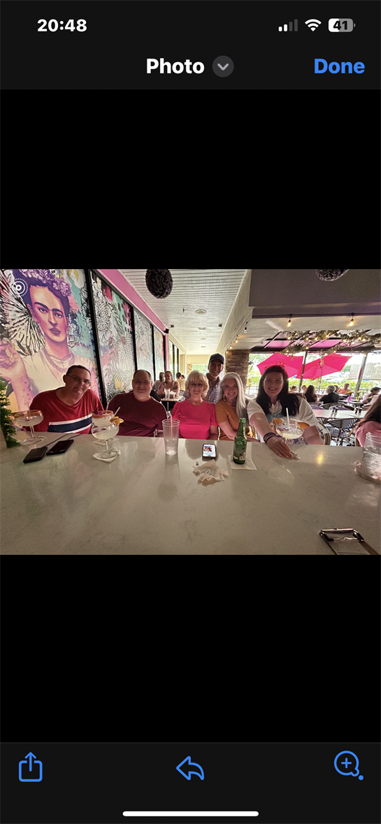 Group of friends sitting at a bar counter, sipping drinks and engaging in cheerful conversation.