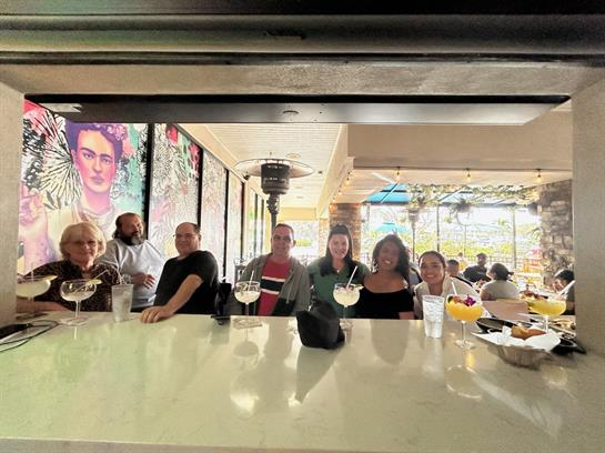 A group of friends sits at the bar, enjoying cocktails and sharing joyful moments together.