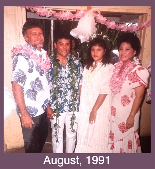 Four family members dressed in colorful attire celebrate together, adorned with floral leis.