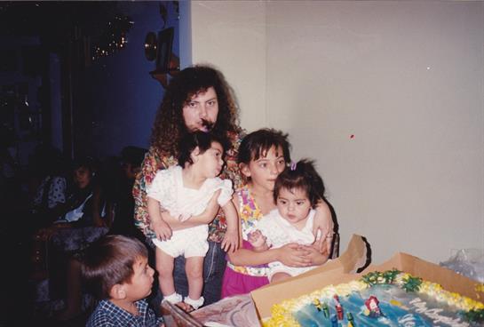 A group of children standing in front of a birthday cake