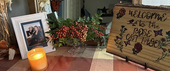 A warm candlelight greets visitors at Rose Cottage, adorned with autumn decor and a cherished photo.