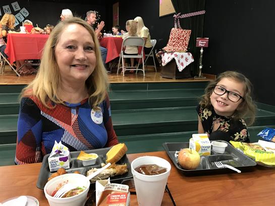 A woman and a girl share a joyful moment while having lunch at a community event.