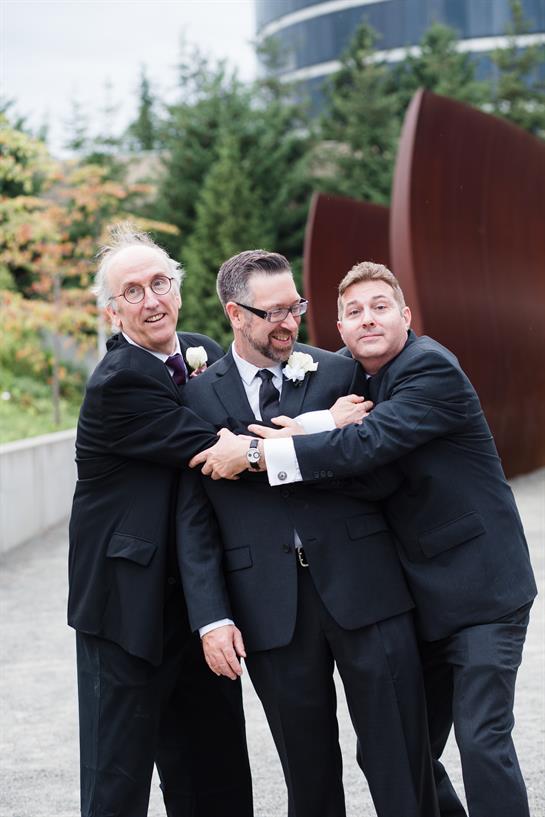 Friends celebrate together with laughter and joy during an outdoor wedding event.