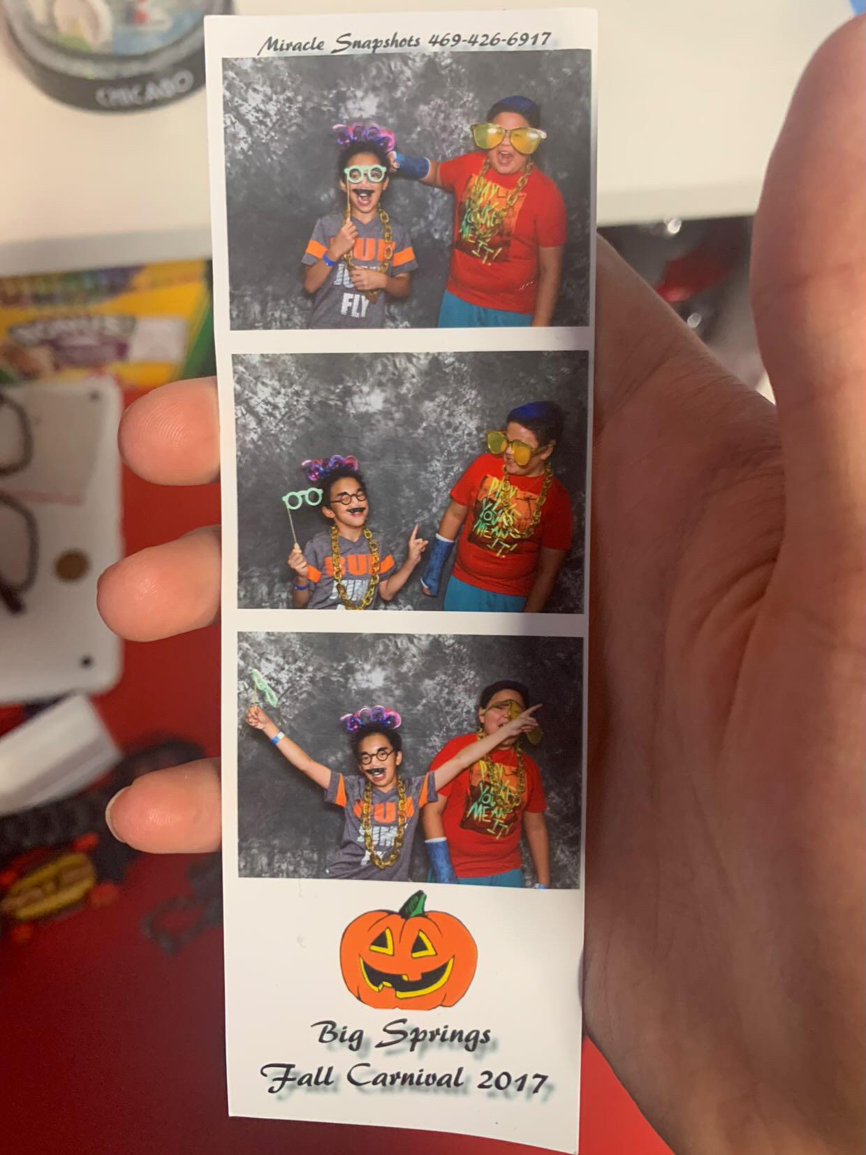 Two kids enjoy their time at the Big Springs Fall Carnival, posing for silly pictures in costumes.