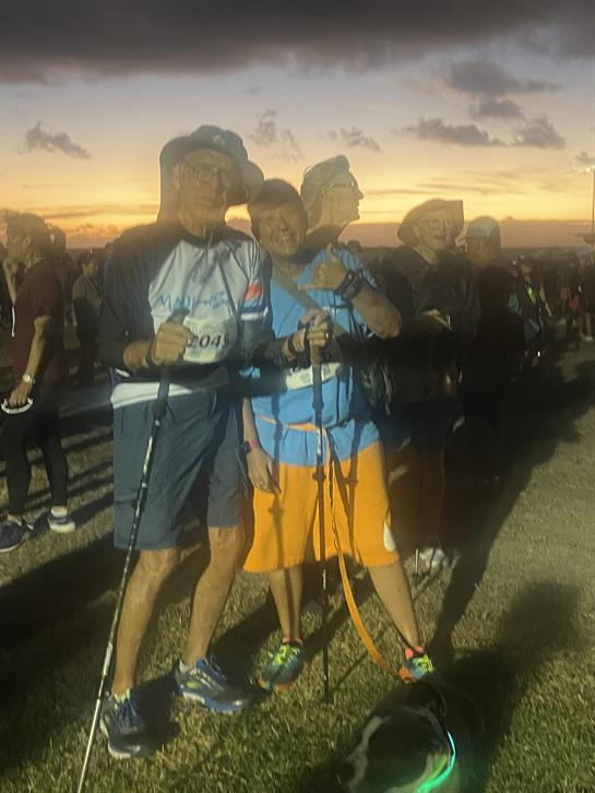 Enthusiastic hikers pose together while showcasing their trekking poles during a vibrant sunset.