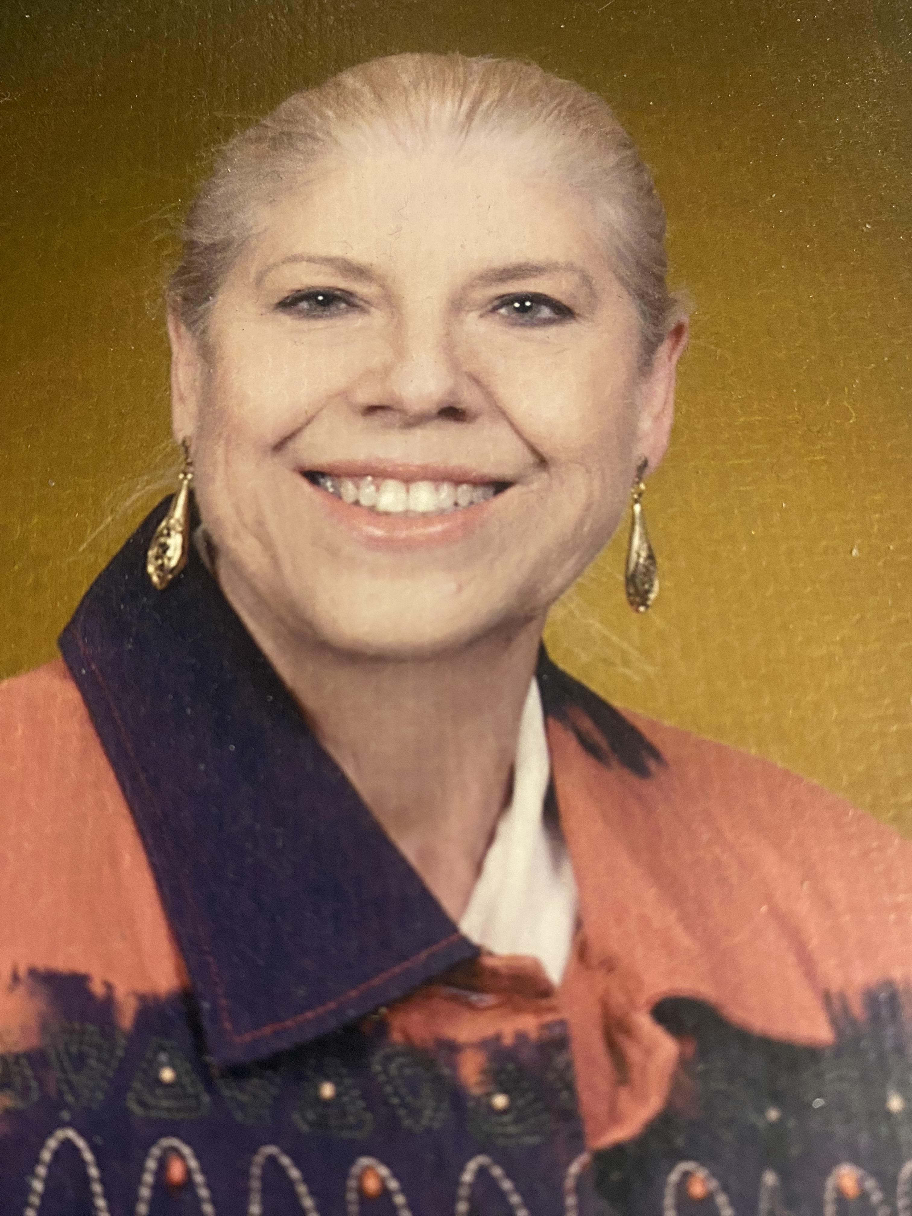 A woman joyfully smiles in vibrant clothing, reflecting her cheerful personality.