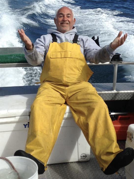 A man in yellow overalls sitting on a boat