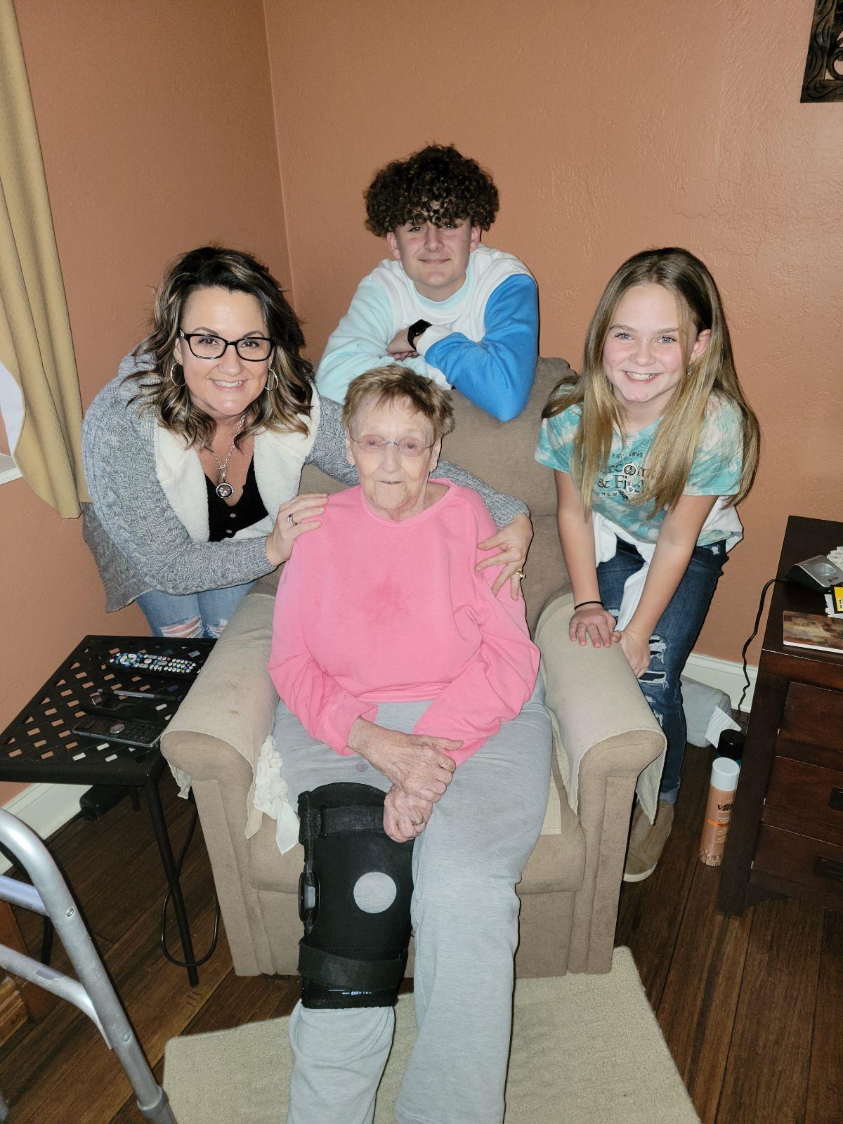 Grandmother sits with her smiling grandchildren and daughter, cherishing a family moment.
