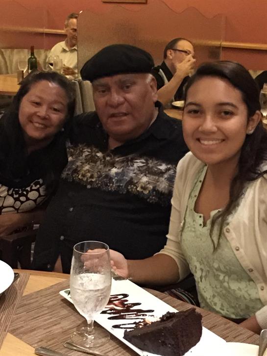 Three family members enjoy a meal together, sharing laughter and conversation in a cozy spot.