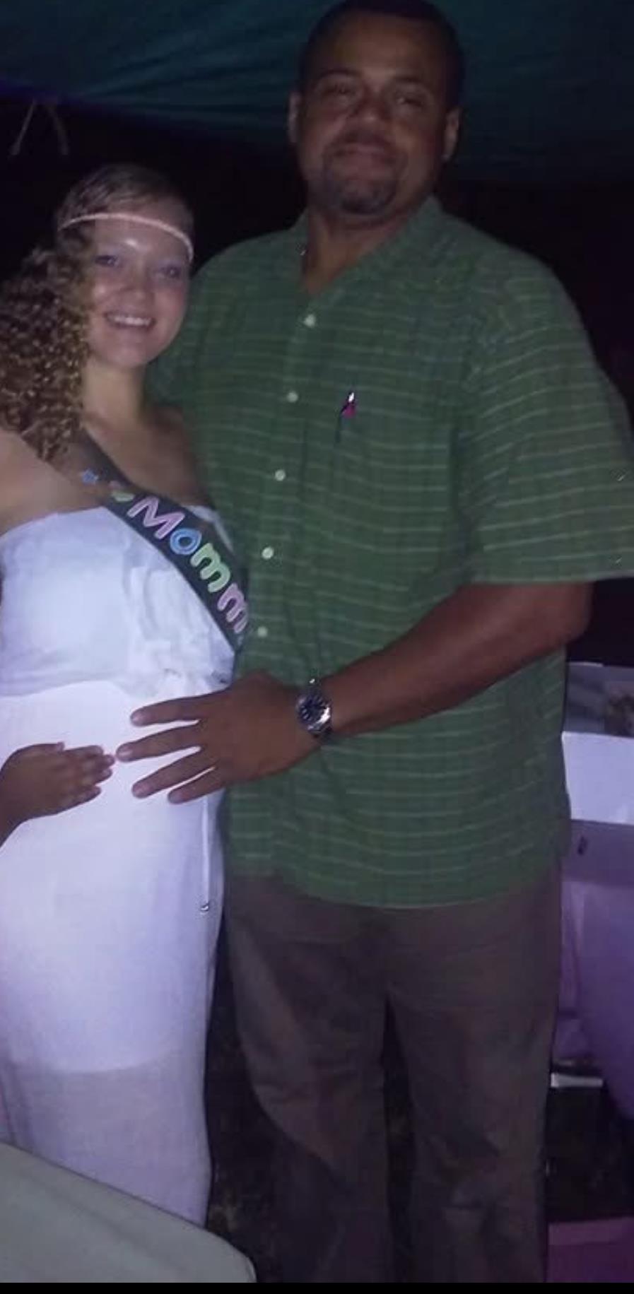 Couple joyfully celebrating the upcoming arrival of their baby during a nighttime event.