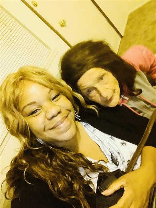 Two women share smiles and laughter in a warm, inviting living space filled with joy.