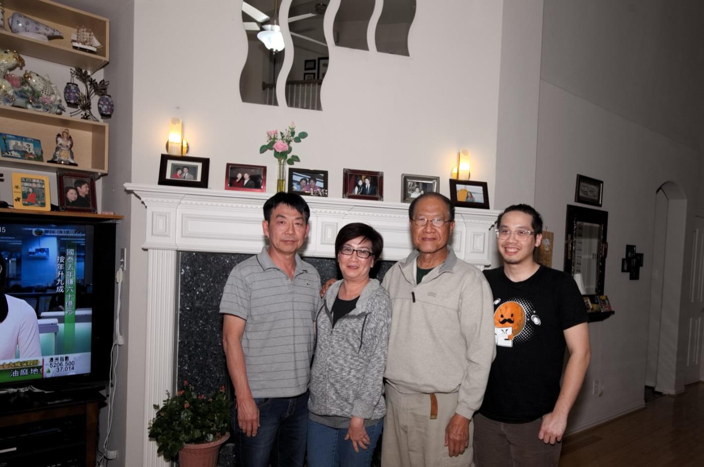 Four family members pose joyfully in a cozy, decorated living room.