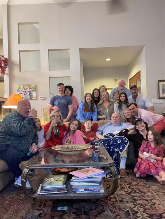Family members joyfully pose together in a warm living room during a special gathering.