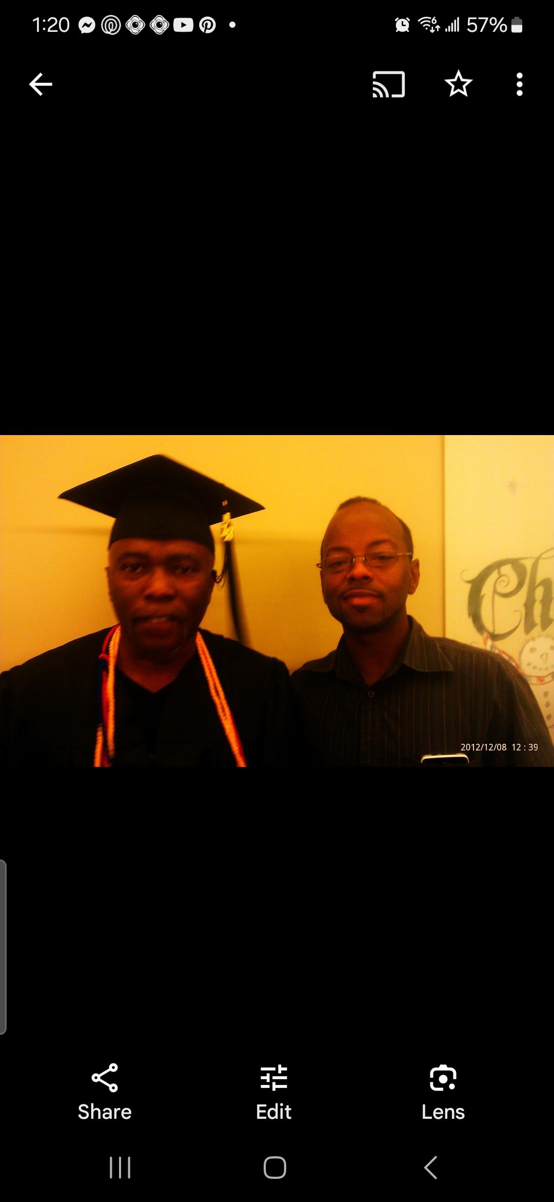 Two men pose together at a graduation ceremony, celebrating a significant achievement.