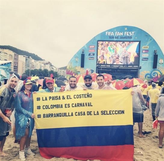 Friends proudly display the Colombian flag while enjoying a beach festival during FIFA Fan Fest.