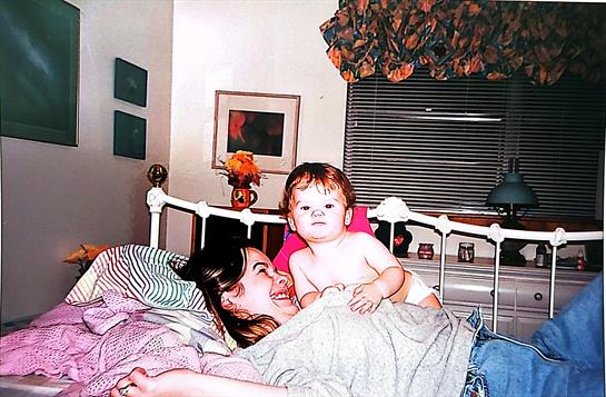 A woman and a baby lying on a bed