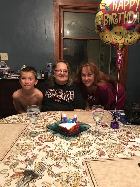 A warm family gathering takes place with smiles and a birthday cake on the table.
