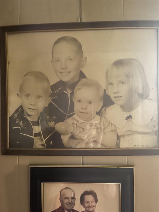Four siblings pose in a black-and-white portrait, capturing their youthful innocence.
