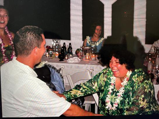 Guests joyfully celebrate in tropical attire and leis while interacting happily.