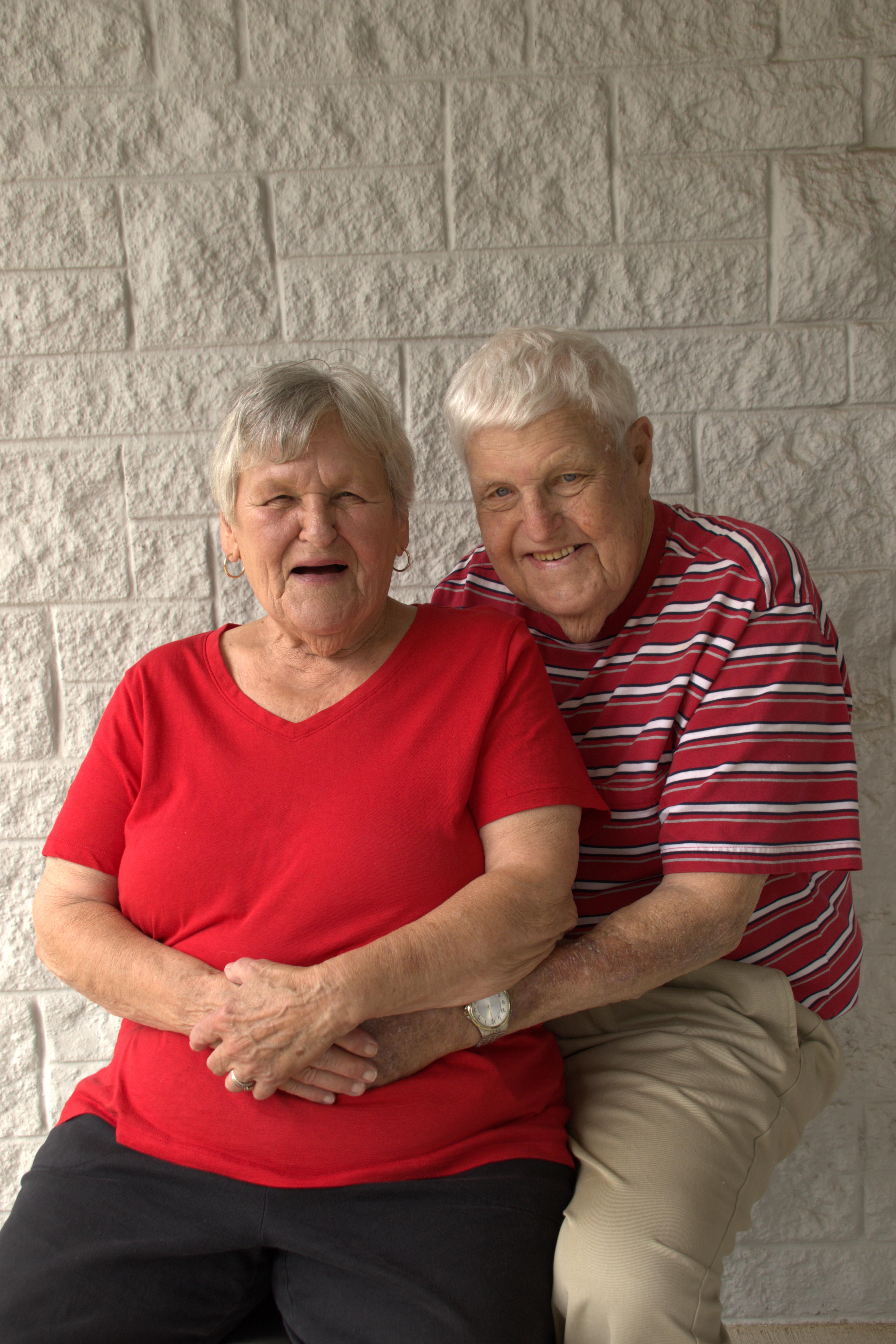 Grandparents smile warmly as they embrace each other in a cheerful, sunny atmosphere.