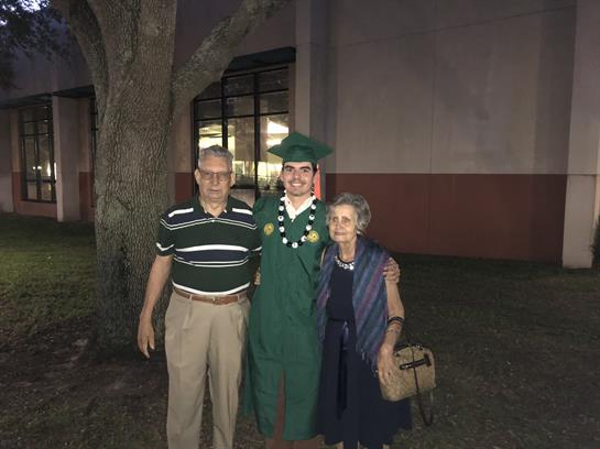Family gathers to commemorate the graduation of a student with proud grandparents in attendance.