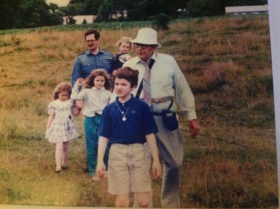A group of children and adults strolls through a grassy area, enjoying quality time together.
