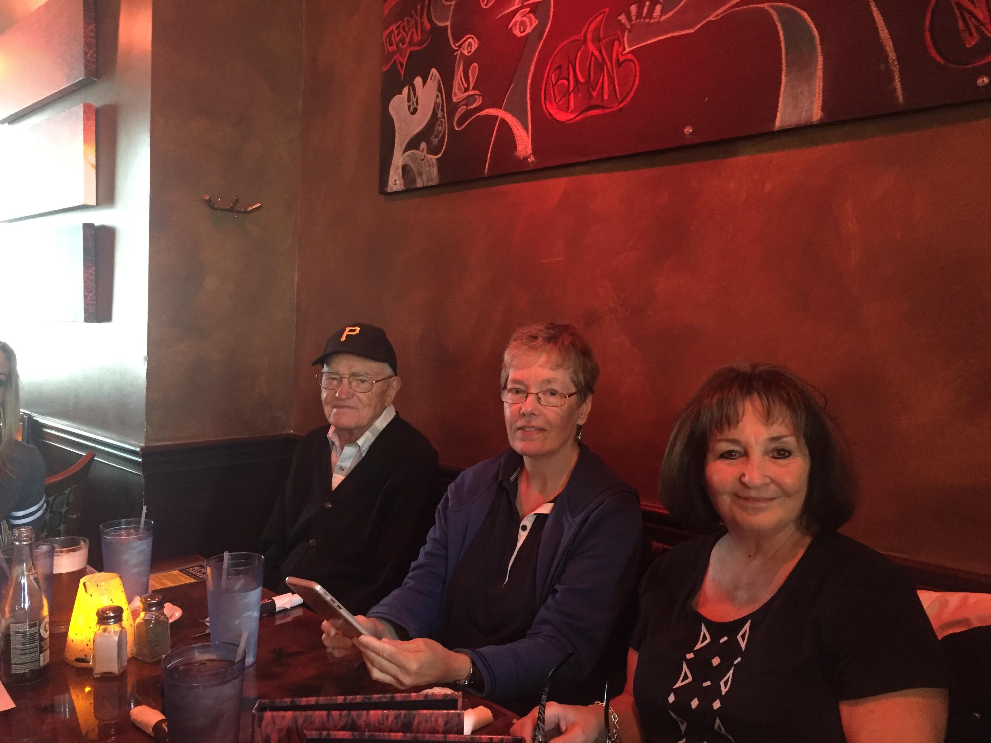 Three people sit at a cozy table in a restaurant, smiling while enjoying their time together.