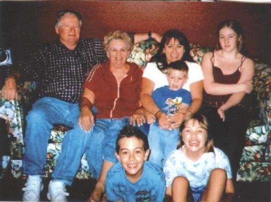 A joyful family gathering featuring children and adults seated on a floral couch indoors.