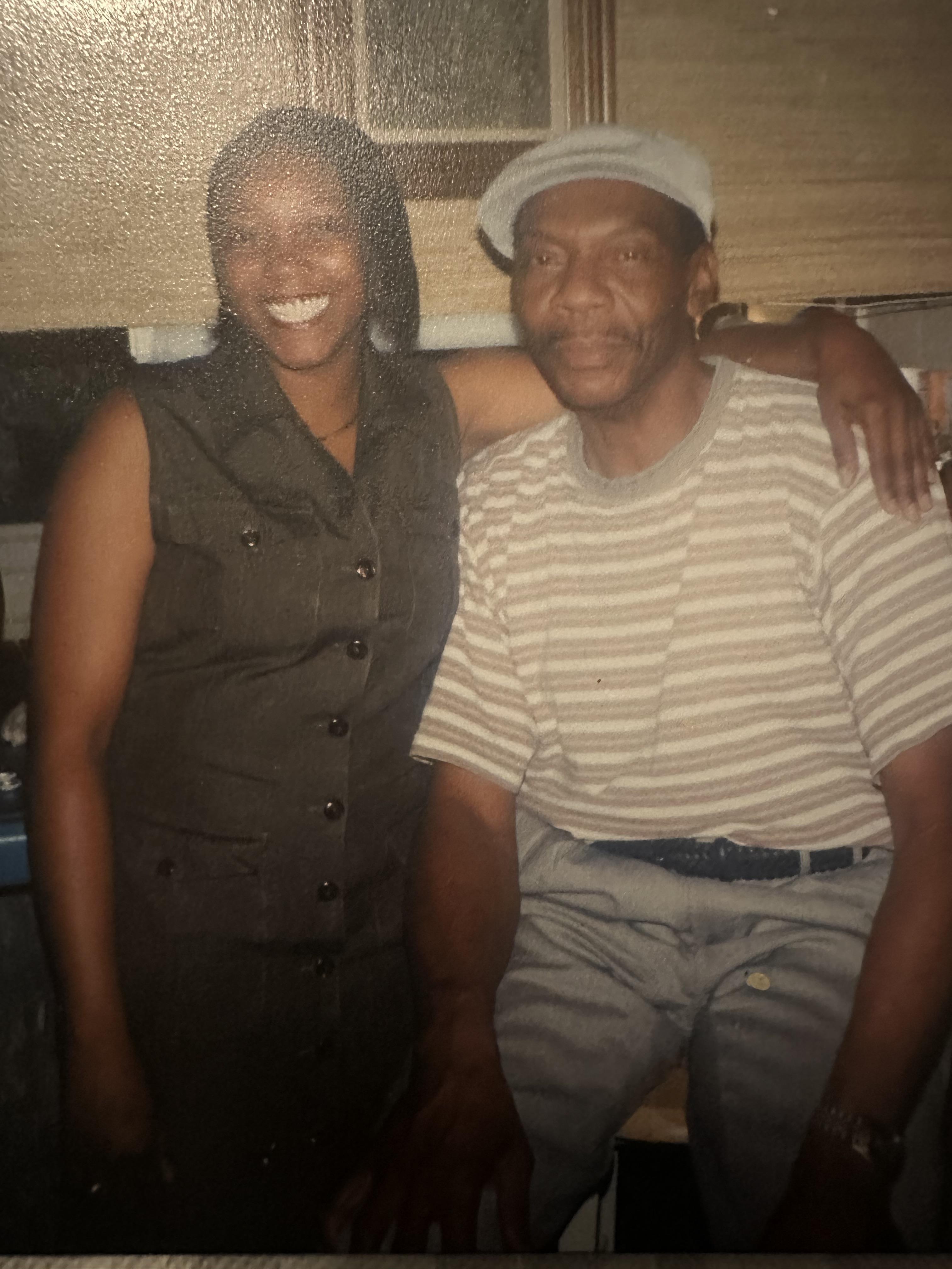 Two friends enjoy each other's company, smiling brightly in a warm kitchen setting.