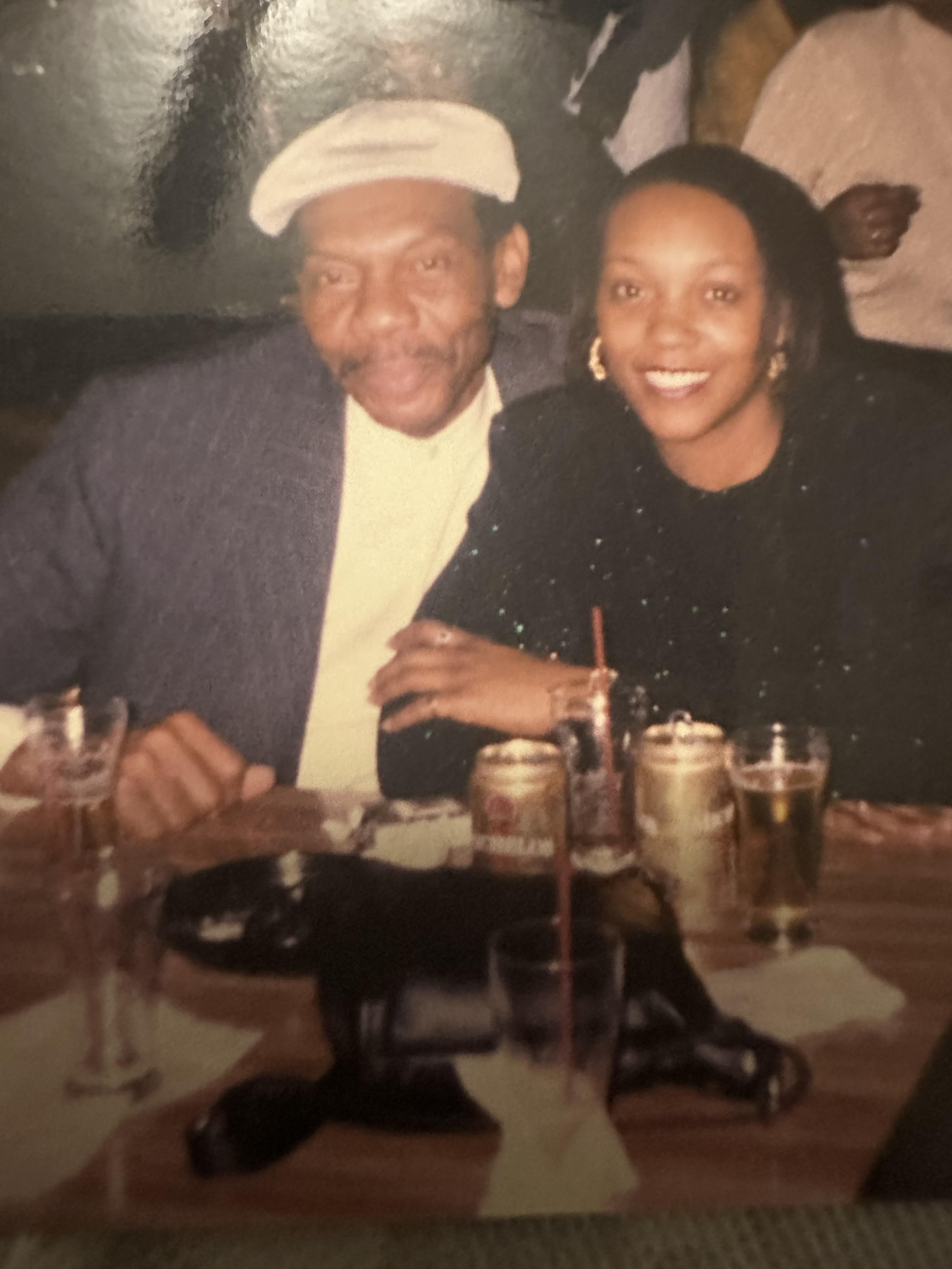 A joyful couple poses together at a lively gathering, surrounded by drinks and smiles.