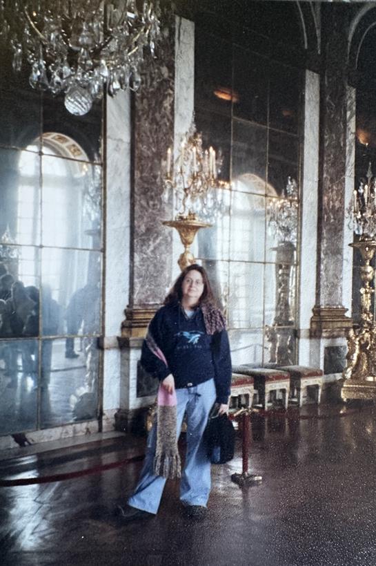 A visitor stands in a luxurious palace hall, surrounded by mirrors and chandeliers.
