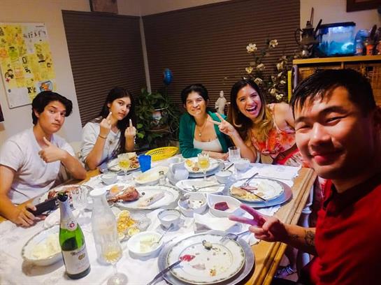 Six friends gather around a table, sharing food and laughter during a relaxed dinner.