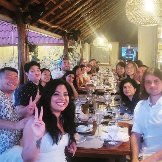 Friends gather around a large table for a joyful dinner, sharing smiles and good times at night.