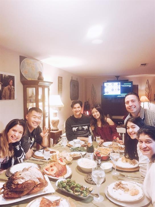 Eight people celebrate Thanksgiving with a festive dinner filled with food and drinks.