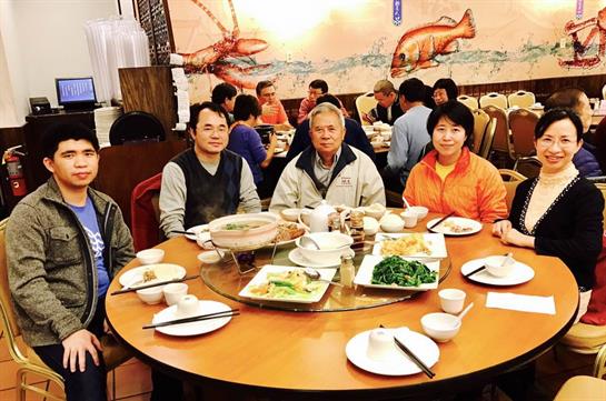 Friends celebrate together with a cozy meal featuring a variety of dishes at a round table.