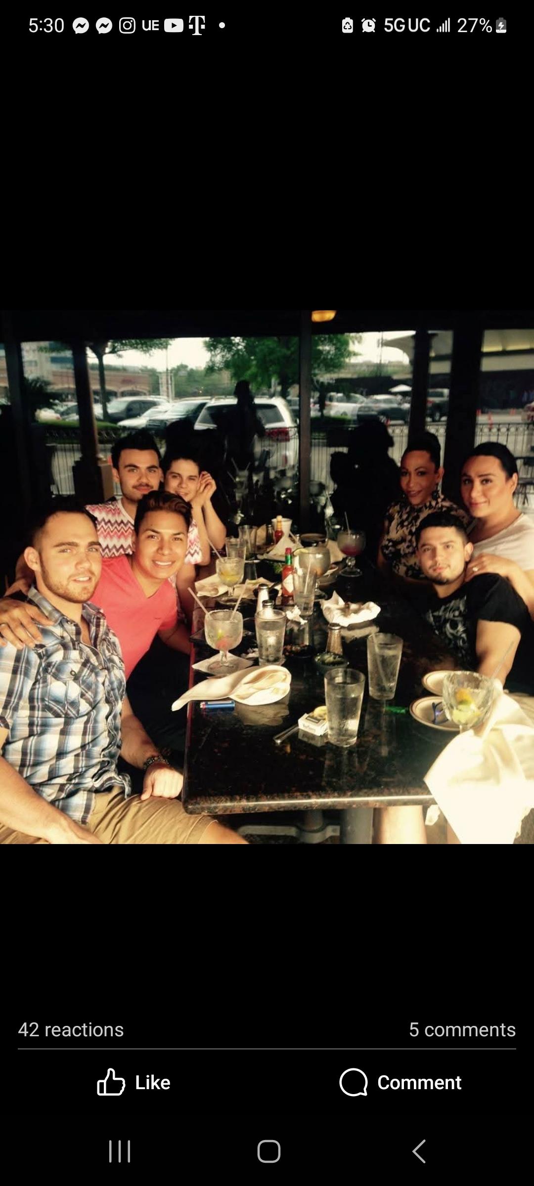 Group of friends sharing laughter and food at a restaurant during a sunny day.