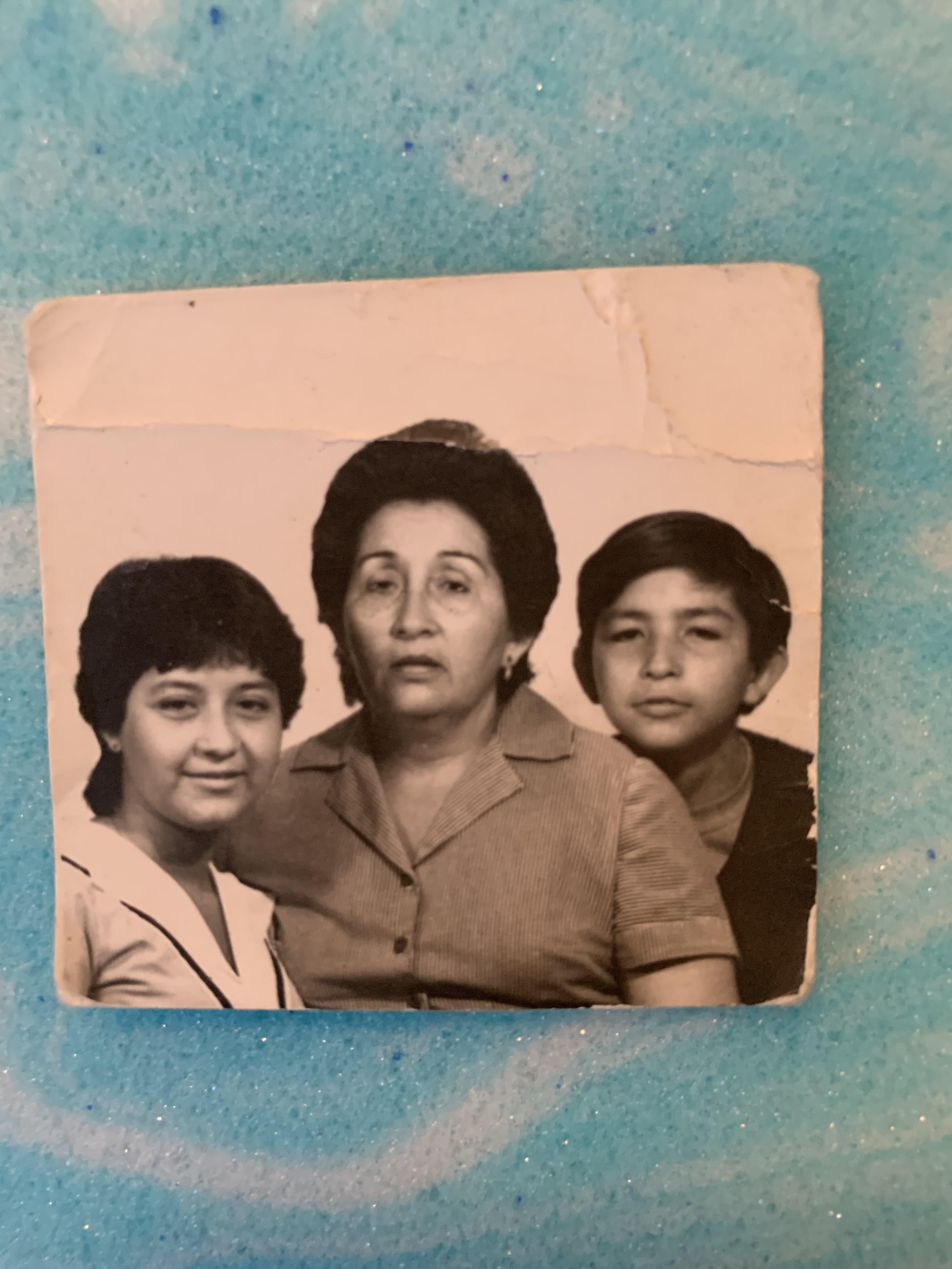 A mother stands with her two children, sharing a moment frozen in time, likely from the past.