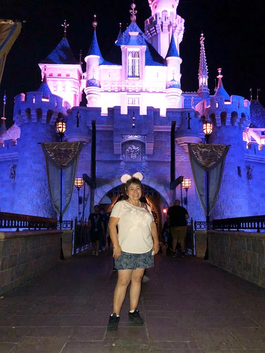 A visitor stands at the castle's entrance, admiring the enchanting lights in the evening.