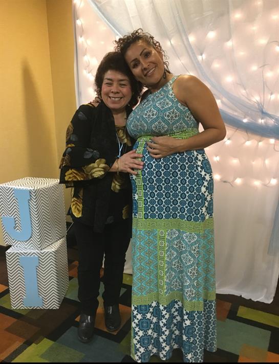 Two women pose joyfully together in vibrant outfits at a festively adorned location.