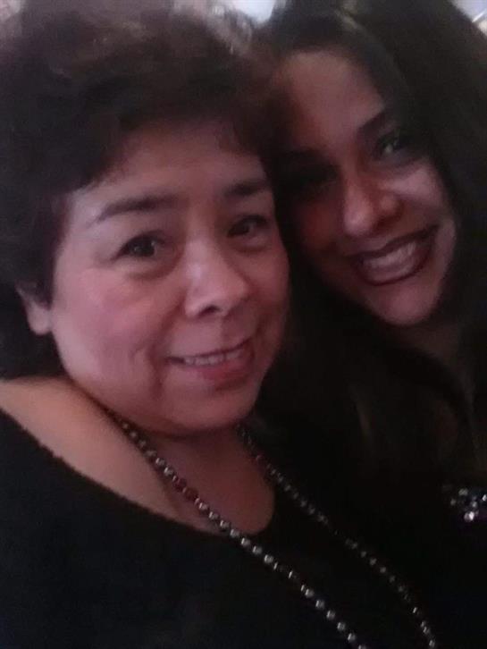 Two women smile warmly at the camera, celebrating together during a nighttime gathering.