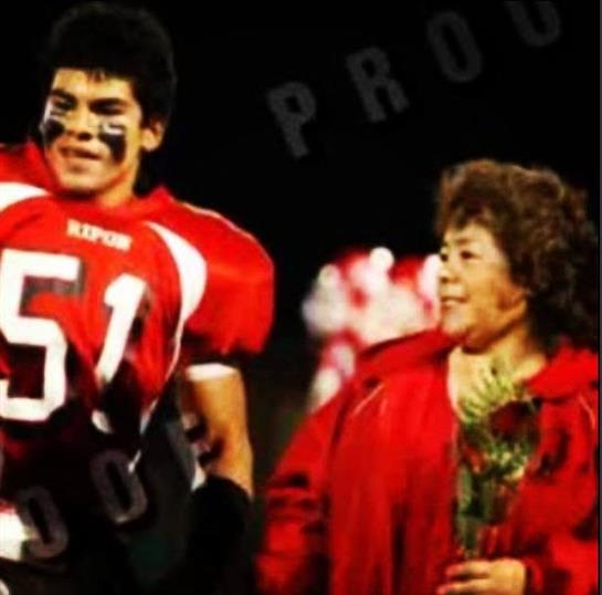 Student athlete honored with flowers and smiles from mom during senior night celebration.