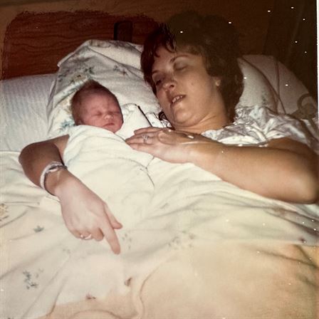 A woman lying in bed with a baby