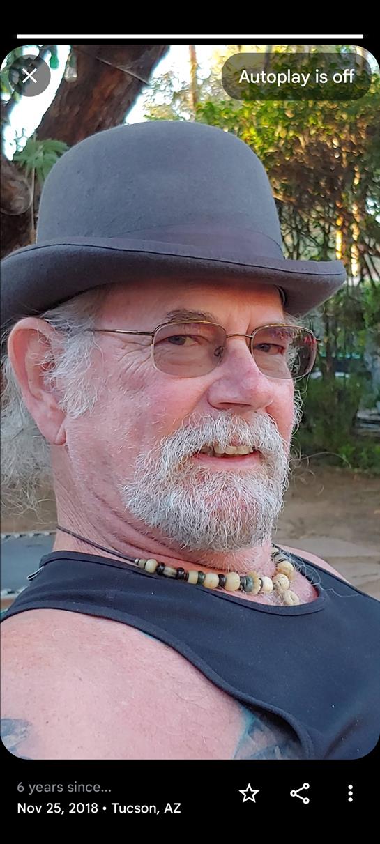 A man with a mustache and beard relaxes in a casual setting, enjoying the pleasant weather.