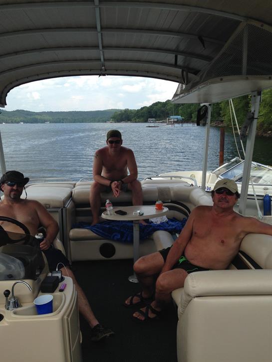 Three friends spend quality time on a pontoon boat while enjoying the lake's beauty.