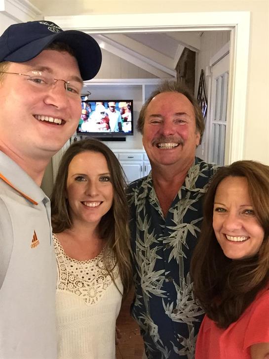 Four family members are smiling and enjoying each other's company in a warm, welcoming space.